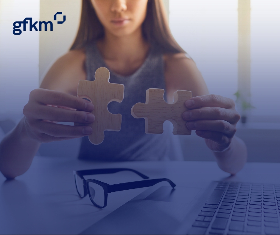 Kobieta składa dwa duże puzzle nad biurkiem.